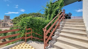 Eine Treppe mit roter Handlauf, die zu einem Balkon mit Schachbrettboden führt.