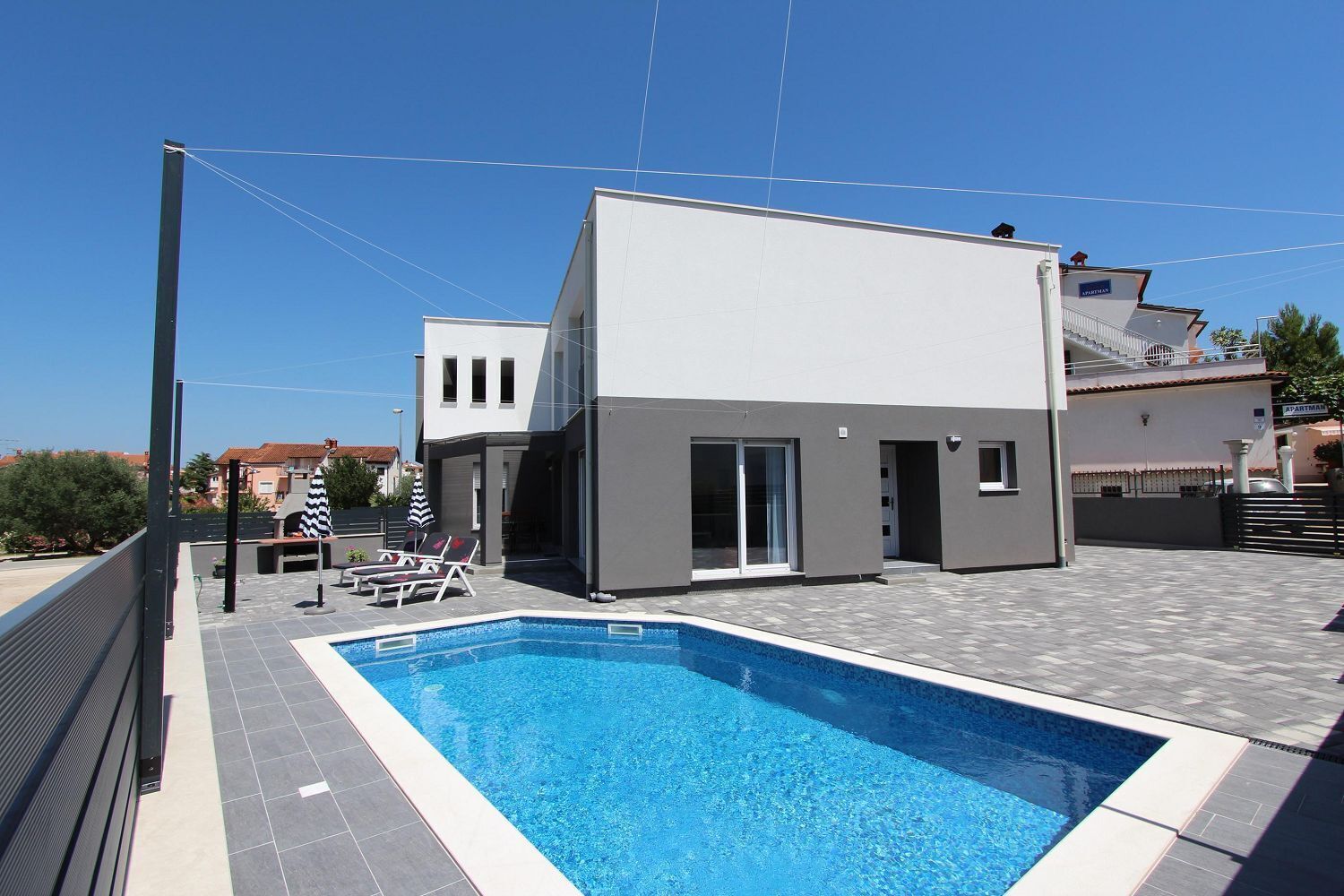 A modern building with a swimming pool, a covered patio, and a view of the surrounding area.