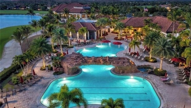 A resort with multiple swimming pools, palm trees, and a golf course in the background. - Bonita National Coach home, offers endless amenities for everyone  (Bonita Springs)