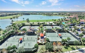 A resort with tennis courts, a pool, and a view of the surrounding landscape.