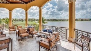 A covered outdoor seating area with chairs and tables, overlooking a body of water and greenery. - Bonita National Coach home, offers endless amenities for everyone  (Bonita Springs)
