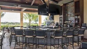 A bar area with a high ceiling, multiple ceiling fans, and a bar counter with stools. - Bonita National Coach home, offers endless amenities for everyone  (Bonita Springs)