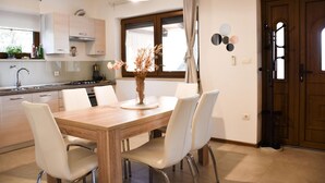 Una cocina moderna con armarios blancos, una mesa de comedor de madera y sillas blancas.