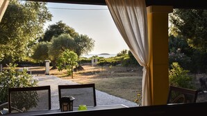 Un área de estar al aire libre con una mesa y sillas, vistas a un viñedo y una estructura de pérgola.