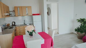 Cocina compacta con armarios de madera, un refrigerador blanco y una zona de comedor con una mesa dispuesta para dos.
