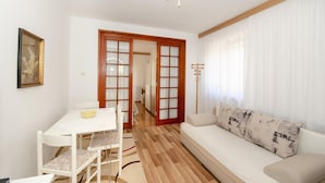 Ein modernes Wohnzimmer mit einem weißen Sofa, einem Esstisch mit Stühlen und Holzboden.