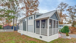 Une maison de plain-pied avec un porche, un petit jardin et une clôture blanche en bois.