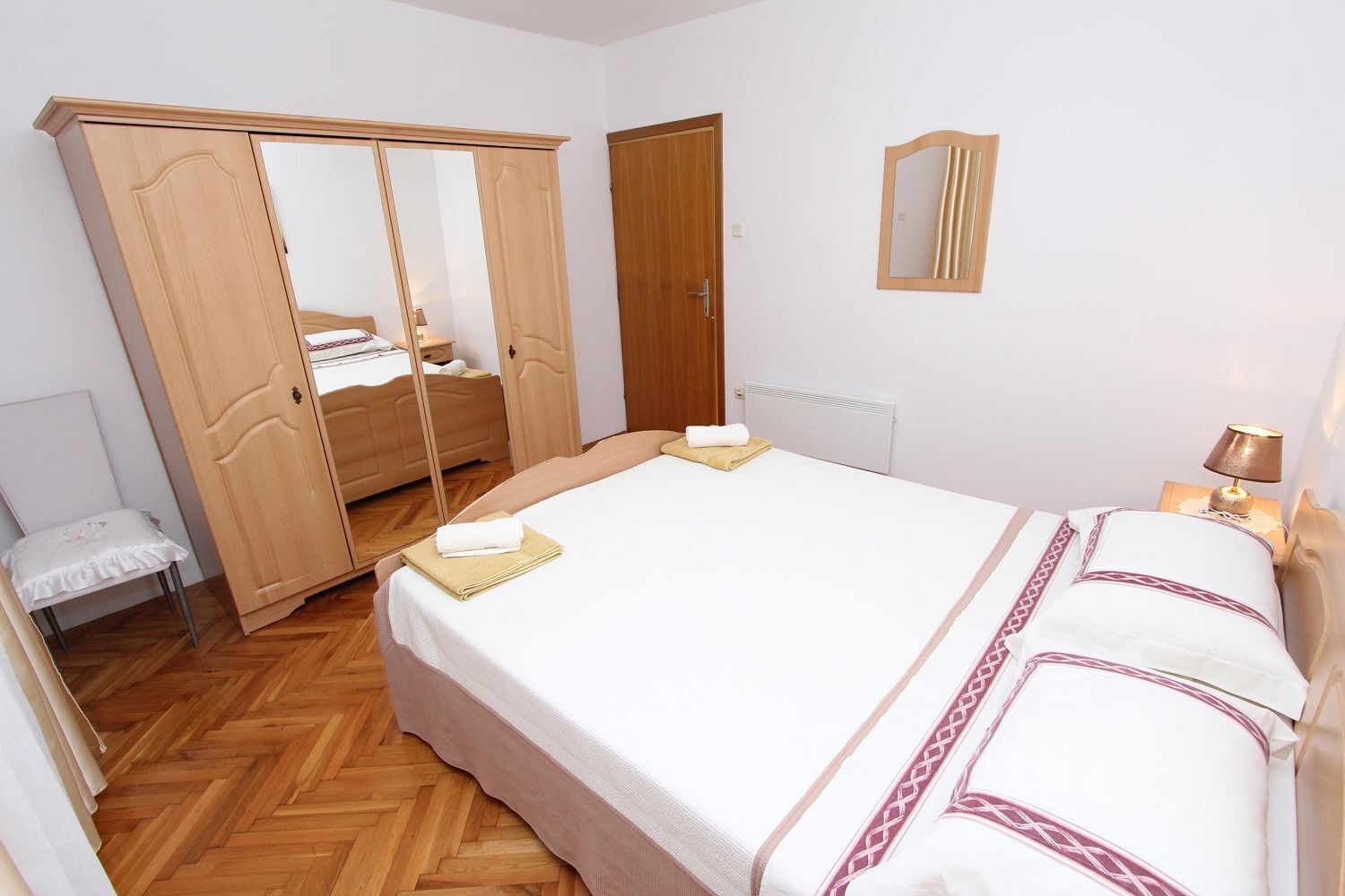 A bedroom with a bed, a wardrobe, a mirror, and a radiator.