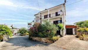 Un bâtiment à deux étages, doté d’un balcon à l’étage supérieur, d’un garage et d’un mur en pierre agrémenté de plantes devant.