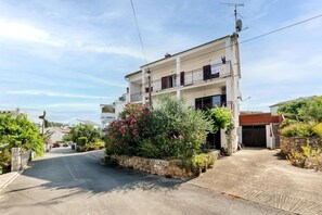 Situated on a quiet street, this two-story residence features a balcony and a garden area with lush greenery.
