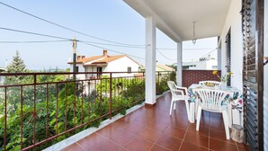 Un balcon fermé avec un sol carrelé, une table avec des chaises et une rambarde.
