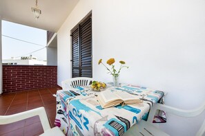 Enjoy a peaceful reading nook on this balcony with a table for two, featuring a vase with flowers and a bowl of fresh fruit.