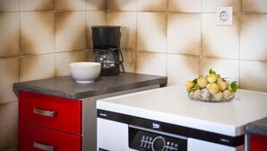 Une cuisine équipée d’une machine à café, d’un saladier et d’un panier à fruits posés sur le comptoir.