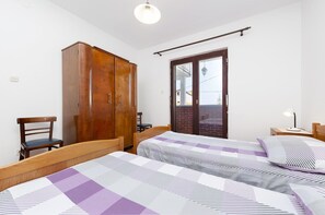 Two single beds with patterned bedding, a wardrobe, and a desk with chair.