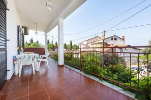 Enjoy the view of the surrounding neighborhood from this balcony with a table and chairs.