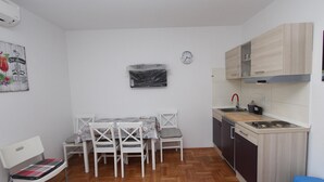 Una cocina compacta con comedor, un reloj en la pared y una pequeña mesa con sillas.