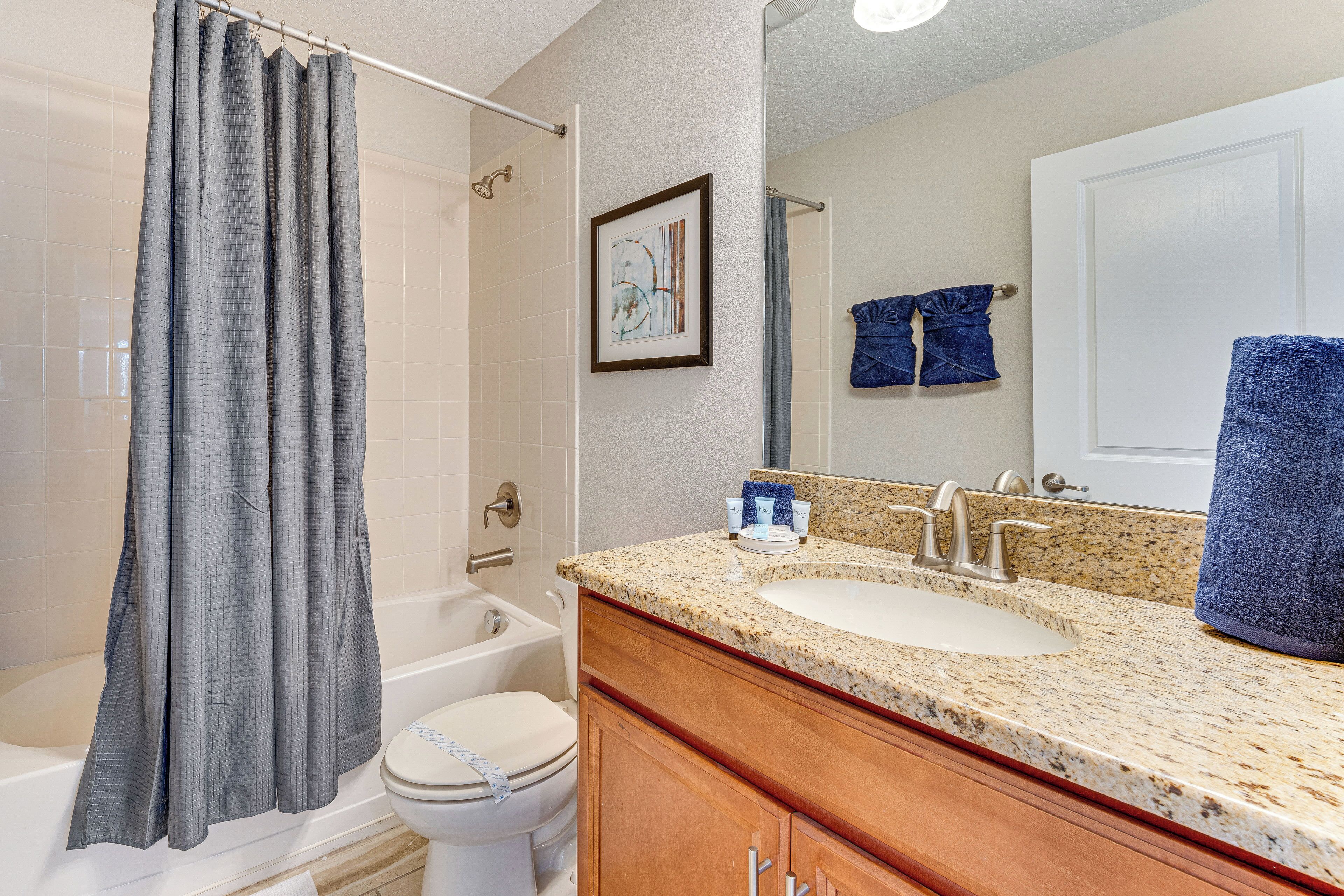 A bathroom with a bathtub, toilet, sink, and a shower curtain.