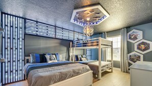 Ein Schlafzimmer mit Etagenbetten, einem großen Bett, einem Schreibtisch und einer Deckenleuchte.