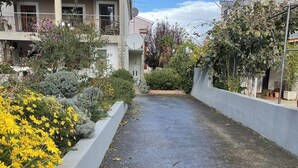 A residential area with a paved driveway, a garden with yellow flowers, and a building with a tiled roof. - Mediterranean apartment with barbecue area, sun loungers in the garden, private parking, WiFi (Rovinj)