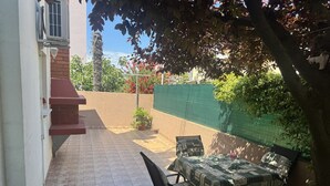A patio with a table and chairs, a brick wall, and a green fence. - Mediterranean apartment with barbecue area, sun loungers in the garden, private parking, WiFi (Rovinj)