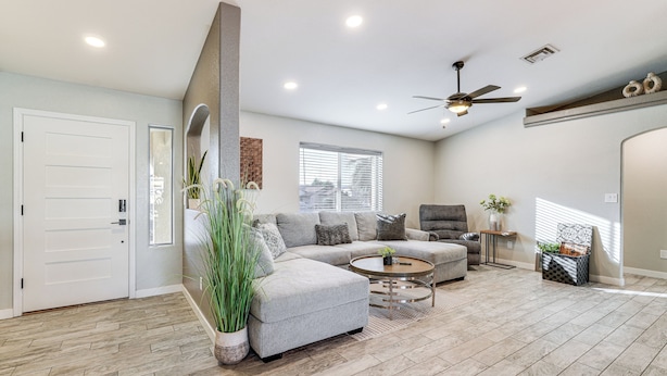A spacious living room with a grey sectional sofa, a round coffee table, and a ceiling fan. - 3 Mi to London Bridge: Home w/ Patio & Grill! (Lake Havasu City)