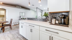 A modern kitchen with white cabinetry, a large island, and pendant lighting. - 3 Mi to London Bridge: Home w/ Patio & Grill! (Lake Havasu City)