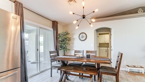 A dining area with a wooden table, chairs, a chandelier, and a clock on the wall. - 3 Mi to London Bridge: Home w/ Patio & Grill! (Lake Havasu City)