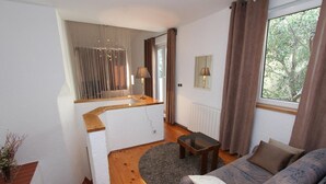 Ein Wohnzimmer mit Sofa, Couchtisch und Blick ins Freie durch ein Fenster.