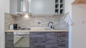 A compact kitchen with a gas stove, a built-in oven, a sink, and dark cabinets.