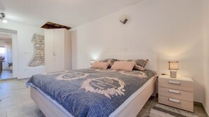 Quarto com cama, mesas de cabeceira e um criado-mudo.