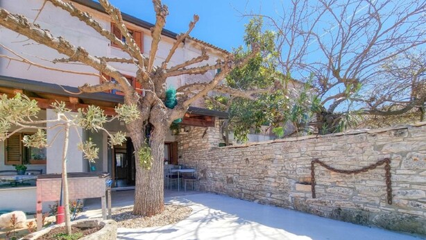 A stone wall, a tree, and a building with a patio.