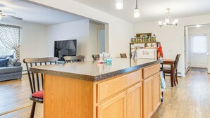 A modern kitchen with a central island, wooden cabinets, and a dining area with a sofa and chairs. - Near Skiing: Serene Harrison Retreat w/ Fire Pit (Harrison)