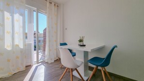 Un comedor con una mesa blanca, sillas azules y una planta en maceta.