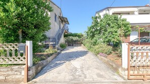 Una estrecha calle adoquinada bordeada por edificios residenciales con balcones, una reja de metal y un pequeño jardín.