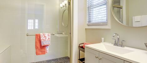 A bathroom with a glass-enclosed shower, a white sink, and a mirror above the sink.