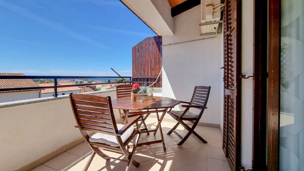 A balcony with a wooden table and chairs, a view of the sea, and a building in the background. - Mediterranean apartment only 700 meters to the beach with sea view, barbecue, private parking (Novigrad)