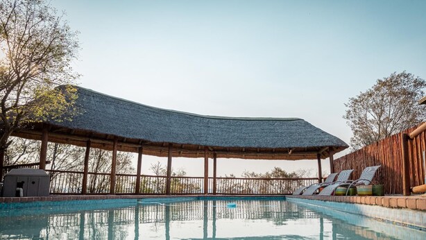 Een zwembadgedeelte met een overdekte zithoek en ligstoelen.