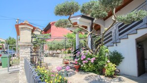 Un quartier résidentiel doté d’un chemin piétonnier dallé, d’une grille en métal et de plantes en pot.