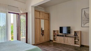 Une chambre à coucher avec un lit, une télévision, des meubles en bois et une porte coulissante donnant sur un balcon.