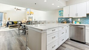 Una cocina moderna con armarios blancos, lavavajillas de acero inoxidable y salpicadero de azulejos azules.