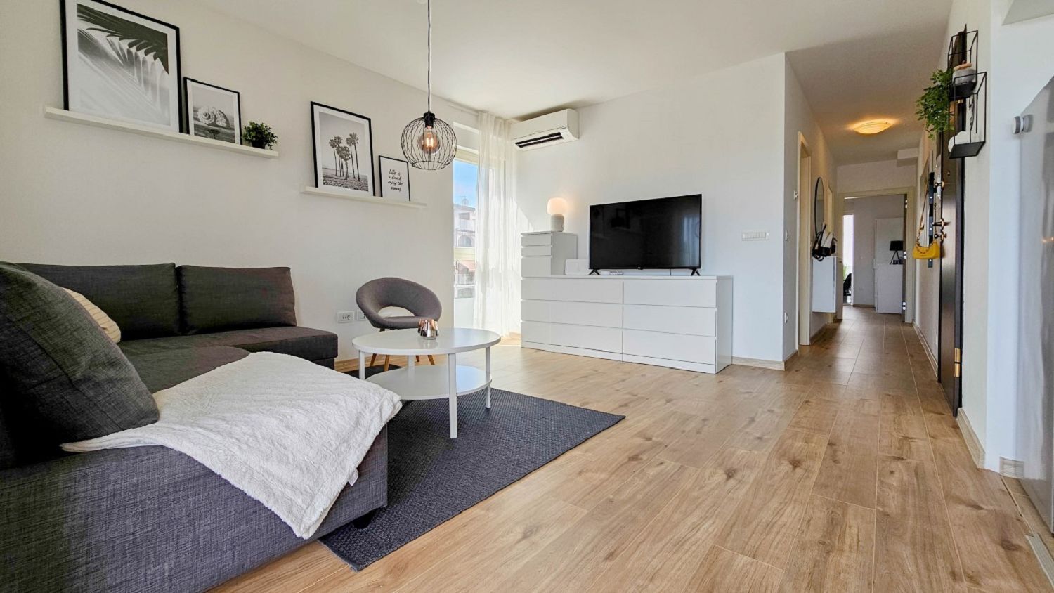 Een moderne woonkamer met een bank, een klein rond tafeltje en een televisie.