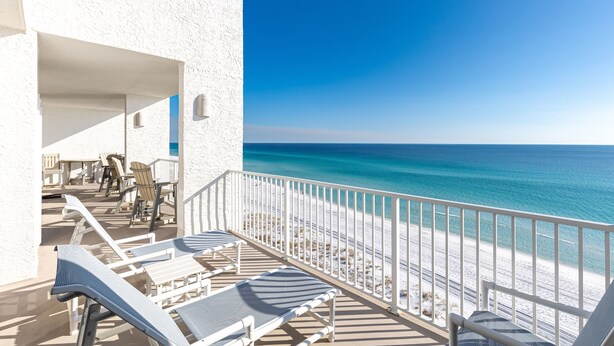 Un balcon avec des balustrades blanches donnant sur une plage.