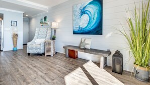 Un salon moderne avec un plancher en bois, un fauteuil à motifs, un banc et un grand tableau abstrait accroché au mur.
