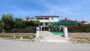 A two-story building with a covered entrance and a stone wall in front.