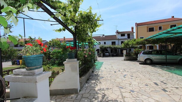 A paved courtyard with stone flooring, potted plants, and a parked car.
