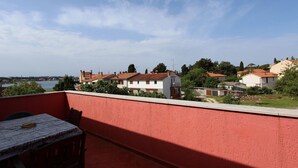 Eine Terrasse mit Tisch und Stühlen mit Blick auf eine Wohngegend mit Häusern und einem Gewässer.