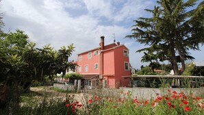 Ein pinkfarbenes Gebäude mit einem Garten davor.