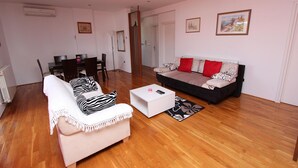 Ein Wohnzimmer mit Sofa, Sessel, Couchtisch und Essbereich mit Tisch und Stühlen.