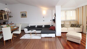 A modern living room with a sofa, a dining table, and a kitchen area.