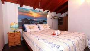 A bedroom with a bed, a globe on a nightstand, a painting of a sunset, and a wooden ceiling. - Idyllic flat just 200 metres from the beach with taxi boat connection to Rovinj (Rovinj)
